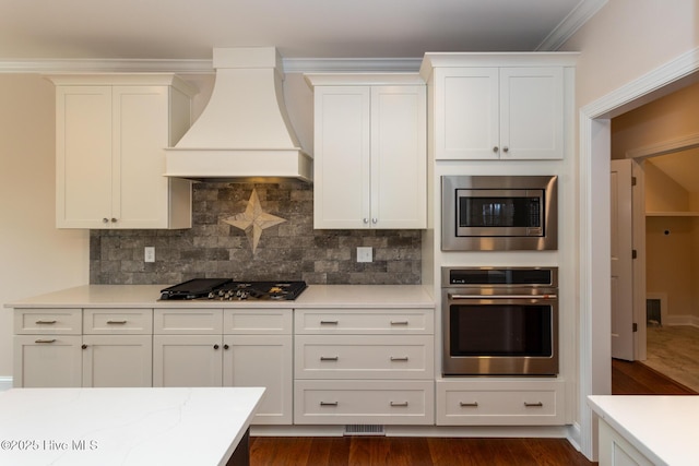 117 Banbridge Dr, West End, NC 27376 - kitchen featuring dark wood-type flooring, custom exhaust hood, backsplash, white cabinets, and appliances with stainless steel finishes