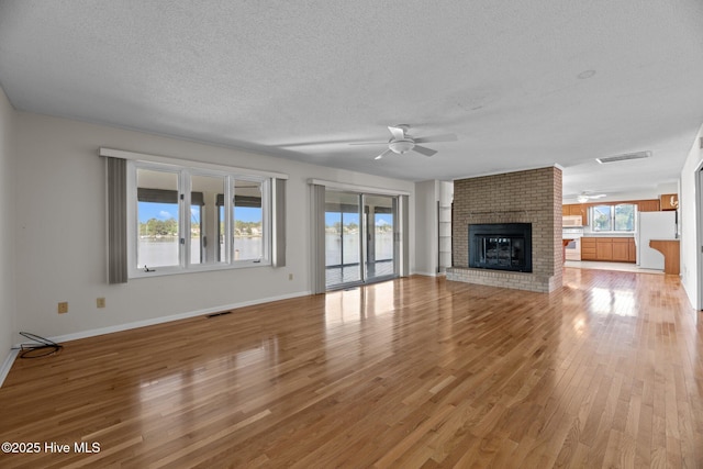 unfurnished living room featuring visible vents, a textured ceiling, ceiling fan, and light wood-style floors