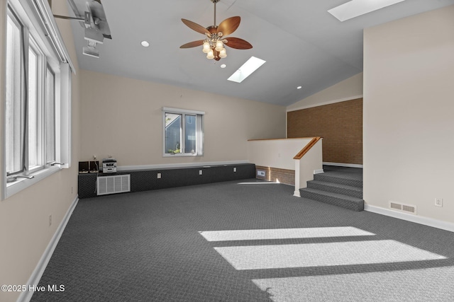 empty room featuring vaulted ceiling with skylight, carpet floors, and a wealth of natural light