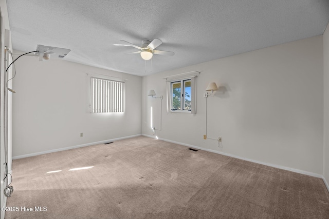 carpeted empty room with a ceiling fan, baseboards, visible vents, and a textured ceiling