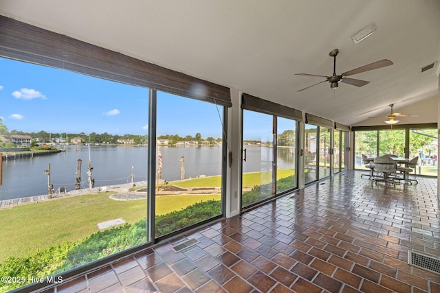 unfurnished sunroom featuring a water view, visible vents, expansive windows, and vaulted ceiling