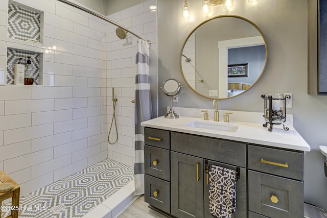 bathroom featuring vanity, a tile shower, and toilet