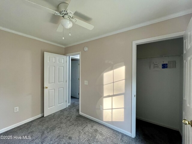 unfurnished bedroom with baseboards, ornamental molding, ceiling fan, carpet floors, and a walk in closet