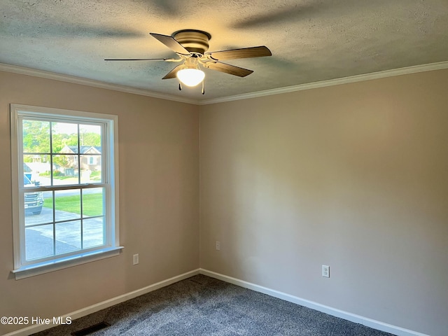 spare room with dark carpet, visible vents, a ceiling fan, ornamental molding, and baseboards