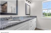 bathroom featuring baseboards, a sink, and double vanity