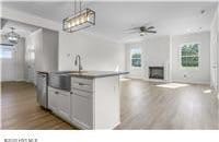 kitchen featuring a sink, open floor plan, pendant lighting, a fireplace, and dark wood finished floors