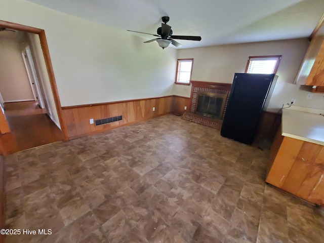 2703 Langston Dr, Goldsboro, NC 27534 - unfurnished living room with a ceiling fan, a fireplace, wood walls, visible vents, and wainscoting