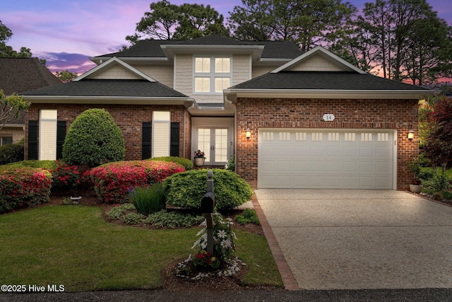 traditional-style home with french doors, concrete driveway, a garage, a lawn, and a shingled roof