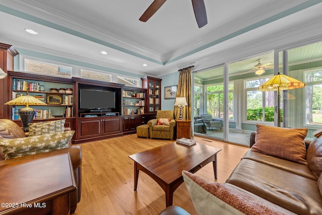 living area with a ceiling fan, ornamental molding, and light wood-style floors