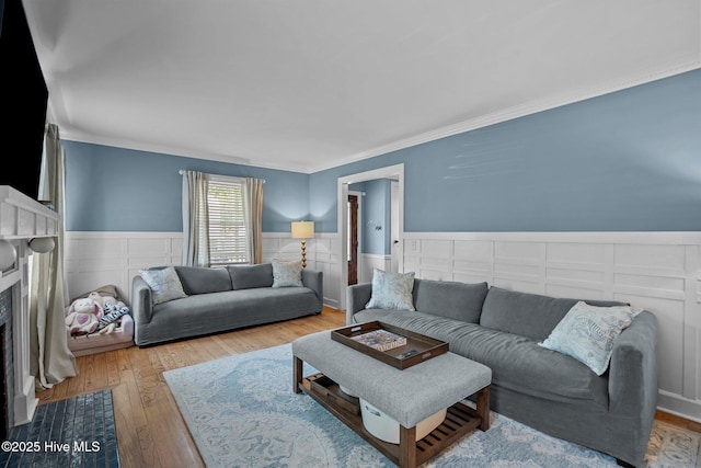 living area featuring crown molding, a wainscoted wall, and wood finished floors