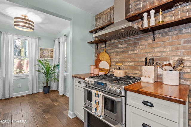 kitchen with wall chimney range hood, wood counters, double oven range, and open shelves