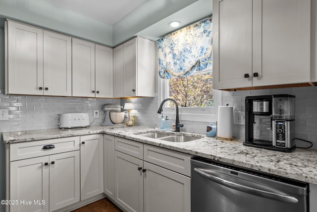 kitchen featuring stainless steel dishwasher, light stone countertops, decorative backsplash, and a sink
