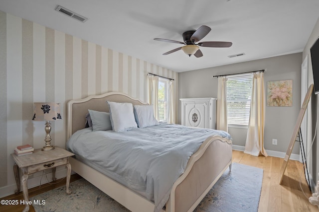 bedroom with baseboards, a ceiling fan, light wood-type flooring, and visible vents