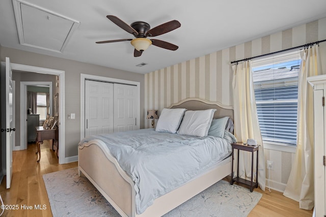 bedroom featuring ceiling fan, visible vents, baseboards, a closet, and light wood finished floors