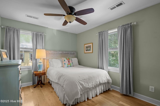 bedroom featuring visible vents, multiple windows, and wood finished floors
