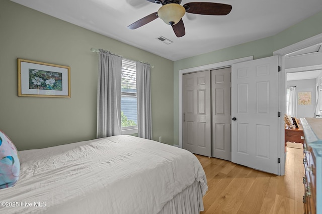 bedroom featuring a ceiling fan, visible vents, light wood finished floors, and a closet