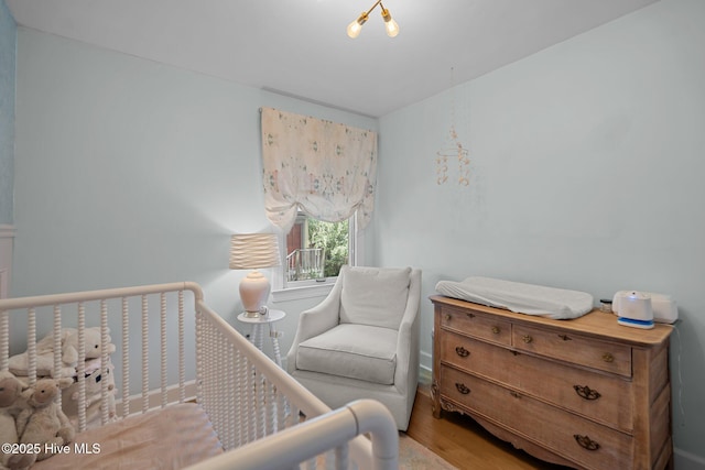 bedroom featuring a crib and wood finished floors