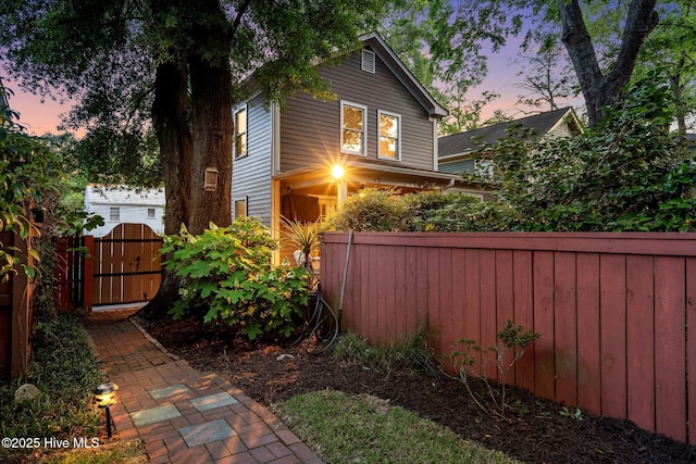property exterior at dusk with fence private yard and a gate
