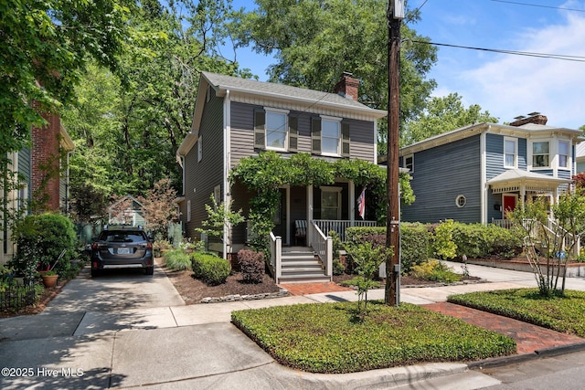 view of front of home featuring a chimney, concrete driveway, and a porch