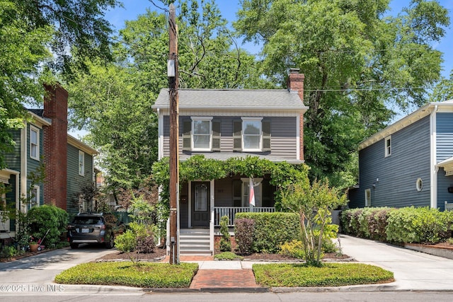 traditional-style house with a porch and a chimney