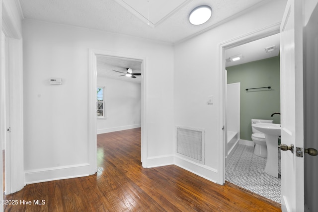 hallway featuring hardwood / wood-style floors, attic access, baseboards, and visible vents