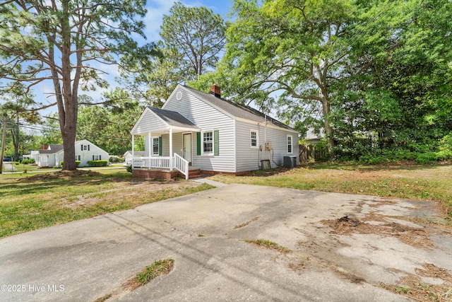 view of front of home featuring a front lawn, roof with shingles, a porch, and central AC unit