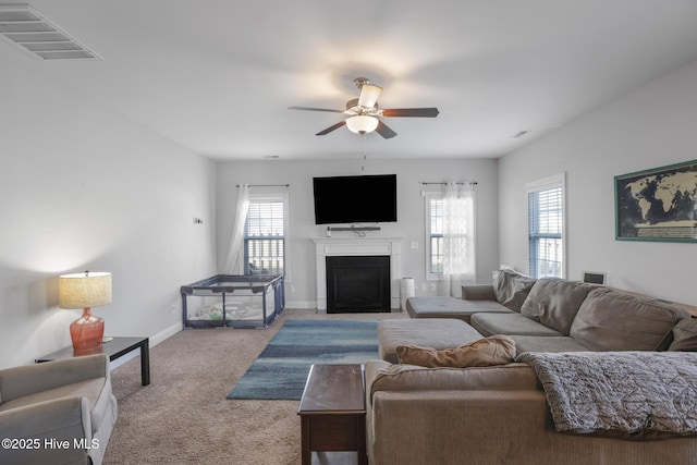living area with ceiling fan, a fireplace, carpet floors, baseboards, and visible vents