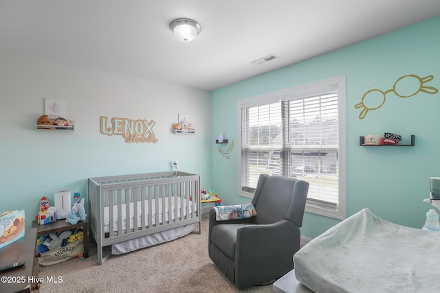 carpeted bedroom featuring visible vents and a crib