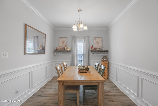 dining area with ornamental molding, a decorative wall, dark wood finished floors, and a notable chandelier
