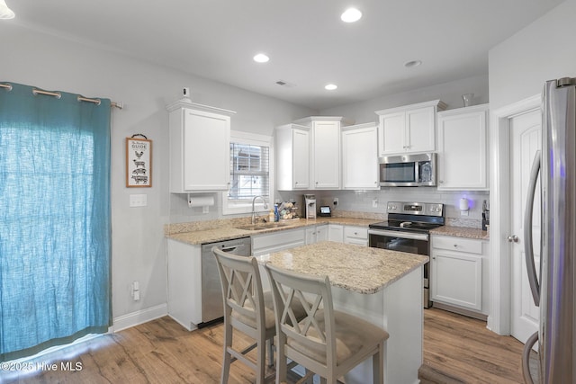 kitchen featuring a sink, white cabinetry, appliances with stainless steel finishes, and wood finished floors