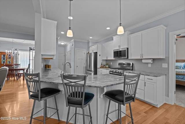 2312 Caracara Dr, New Bern, NC 28560 - kitchen featuring appliances with stainless steel finishes, white cabinets, a breakfast bar, light wood-style flooring, and a sink