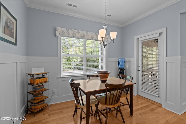 2312 Caracara Dr, New Bern, NC 28560 - dining space featuring a chandelier, light wood-style floors, ornamental molding, plenty of natural light, and wainscoting