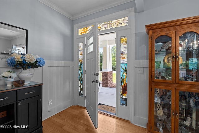 entryway featuring light wood-style flooring, wainscoting, and ornamental molding