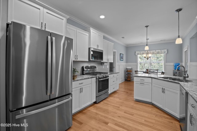 2312 Caracara Dr, New Bern, NC 28560 - kitchen with stainless steel appliances, a sink, crown molding, wainscoting, and light wood finished floors