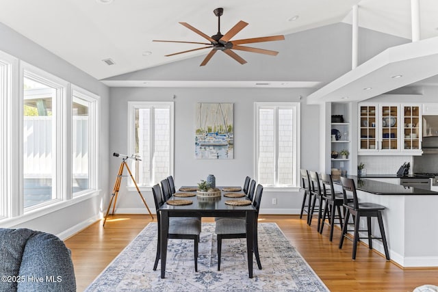 dining space with light wood-style floors, ceiling fan, vaulted ceiling, and a healthy amount of sunlight