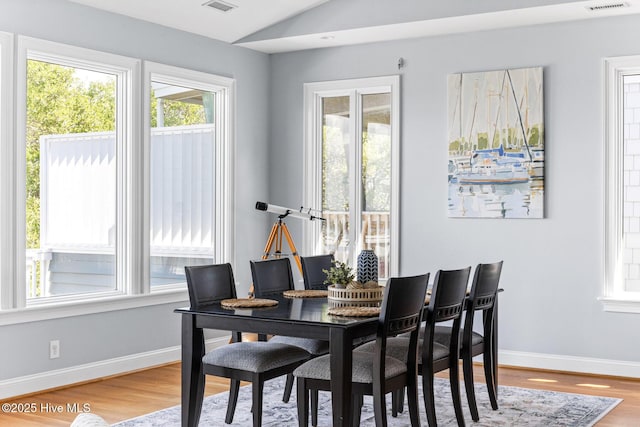dining area with plenty of natural light, light wood-style floors, baseboards, and vaulted ceiling