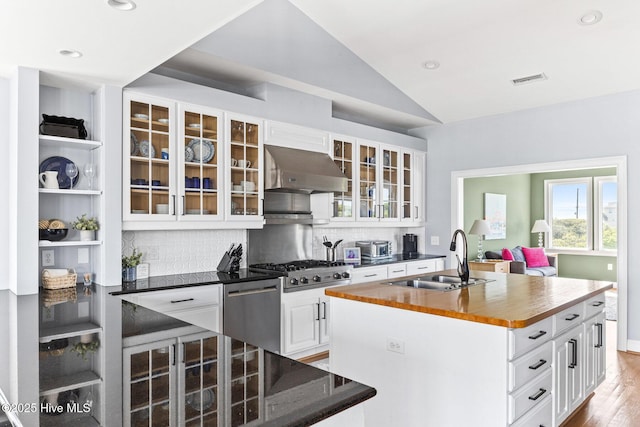 kitchen with a sink, butcher block countertops, stainless steel appliances, range hood, and backsplash