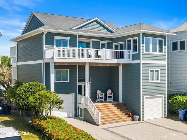 coastal inspired home with an attached garage, a balcony, and concrete driveway