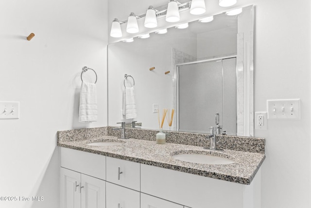 bathroom featuring a sink, a shower stall, and double vanity
