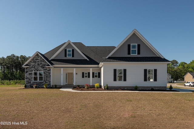 view of front facade featuring covered porch, a front yard, and roof with shingles