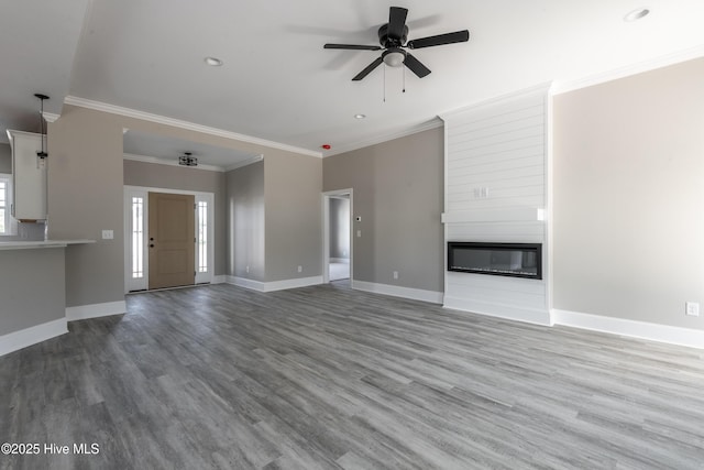 unfurnished living room featuring ornamental molding, baseboards, wood finished floors, and ceiling fan