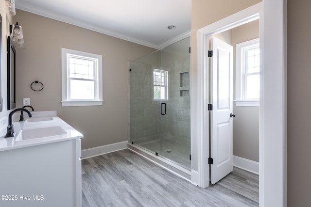 full bath with a shower stall, wood finished floors, ornamental molding, and a sink