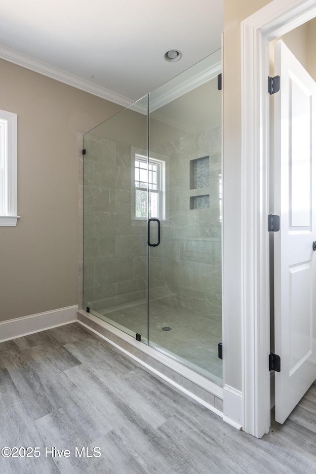 full bath featuring baseboards, wood finished floors, a shower stall, and ornamental molding