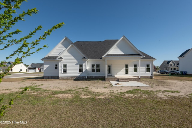 rear view of house with a porch, a lawn, and roof with shingles