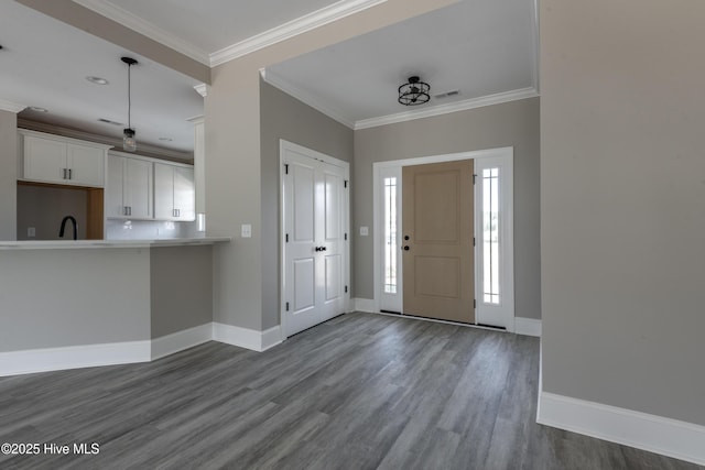 foyer with ornamental molding, baseboards, dark wood-style flooring, and visible vents