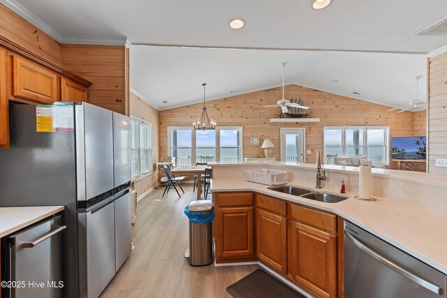 6621 W Beach Dr, Oak Island, NC 28465 - kitchen with stainless steel appliances, wood walls, a sink, a ceiling fan, and healthy amount of natural light