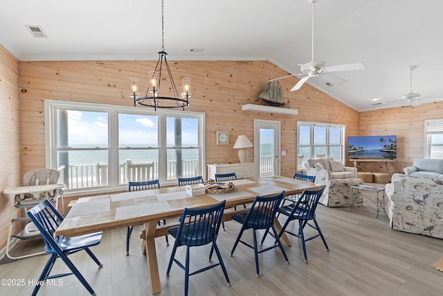 6621 W Beach Dr, Oak Island, NC 28465 - dining area featuring wood walls, lofted ceiling, a chandelier, a ceiling fan, and light wood-style floors