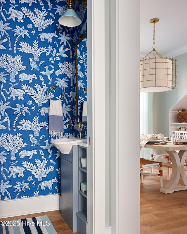 bathroom featuring wood finished floors, crown molding, and baseboards