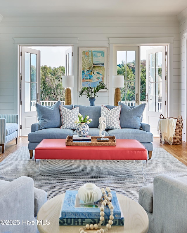 living room featuring ornamental molding, wood finished floors, and wooden walls
