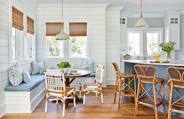 dining area featuring breakfast area, light wood-style floors, and ornamental molding